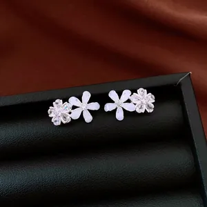 Detail shot of zircon and resin flower stud earrings on a black leather jewelry box
