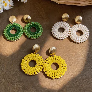 Detailed view of handmade beaded round earrings in green, white, and yellow
