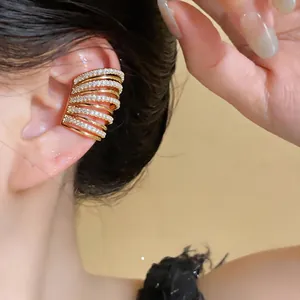 Dettaglio di un ear cuff multistrato placcato oro con pietre di zircone scintillanti.