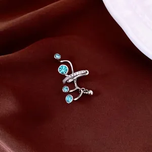 Ear cuff in argento con zirconi blu e piccoli cristalli su sfondo di seta marrone