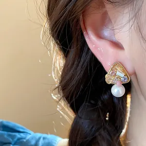 Close-up of a 18k gold-plated geometric earring with colorful crystals and pearl
