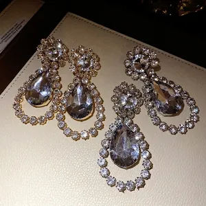 Sparkling teardrop crystal drop earrings with elegant rhinestone floral accents on silver studs.