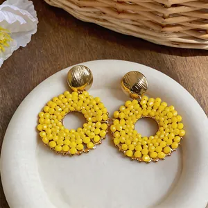 Close-up of vibrant yellow beaded circular earrings with elegant gold stud finish.