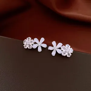 Close-up of elegant flower stud earrings featuring zircon and resin petals on silver needles