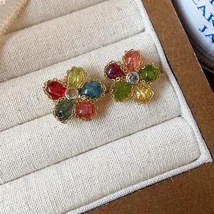 Detail of vintage-style flower stud earrings with colorful zircons in a beige tray