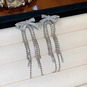 Detailed view of elegant silver-tone bow tassel earrings with sparkling zircon inlay