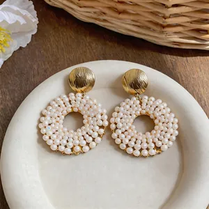 Detail shot of elegant circular stud earrings with gold hammered discs and white pearls