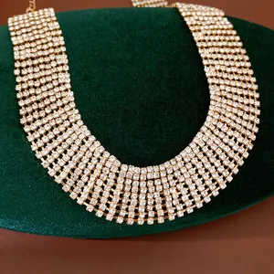 Detail showing multi-row crystal rhinestone tassel collar necklace on green velvet