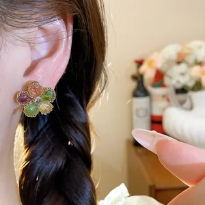 Close-up of vintage flower earrings with colorful zircon stones on model's ear