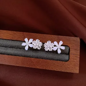 Detail shot of elegant flower stud earrings with zircon and resin on a wooden jewelry tray