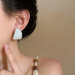 Close-up of elegant C-shaped silver needle earring with mother-of-pearl inlay.