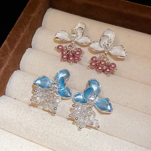 Close-up of elegant floral enamel earrings with dangling pearls and crystals in a box