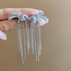 Close-up detail of elegant 18k gold plated bow stud earrings with sparkling zircon tassels