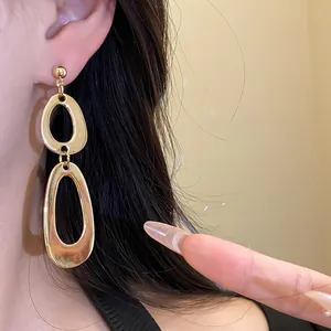Close-up of retro style irregular gold double oval drop earrings on a model's ear