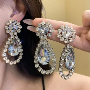 Close-up detail showing the sparkling teardrop crystal facets of luxury earrings