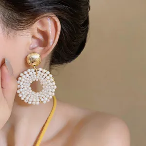 Close-up of elegant gold stud earrings featuring a white pearl-encrusted open circle