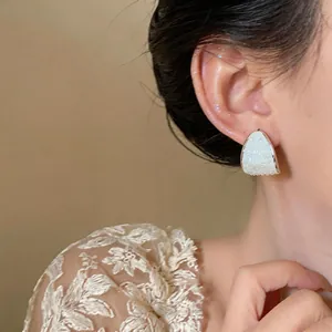 Close-up of elegant C-shaped silver stud earrings with mother of pearl inlay on model