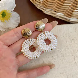 Detailed shot of white pearl beaded hoop earrings with golden textured metal discs.