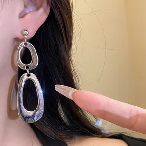 Close-up of irregular silver-tone dangling earrings with hammered metal texture