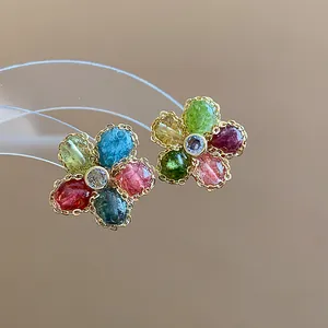 Close-up of retro flower stud earrings featuring colorful zircons in a gold frame