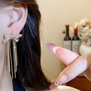 Detailed view of 18k gold plated zircon bow earrings with tassels worn on ear