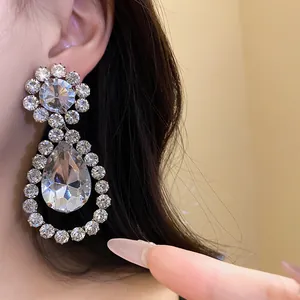 Detailed view of luxury sparkling rhinestone teardrop pendant earrings worn on an ear
