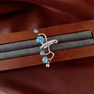 Dettaglio di un earcuff in argento con zirconi blu e cristalli su supporto in legno