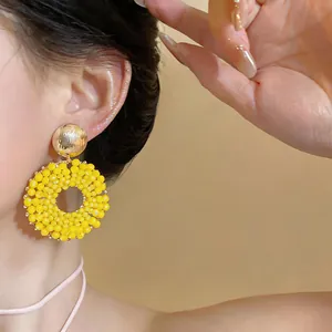Detailed close-up view of vibrant yellow beaded circular earrings worn by a model