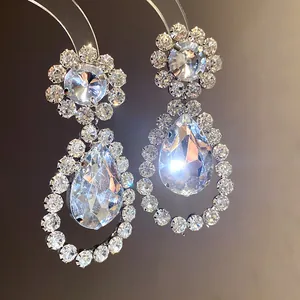 Macro view of crystal drop earrings featuring pear-shaped stones and rhinestone halos