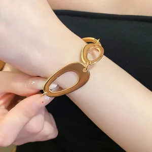 Close-up detail of irregular gold oval link bracelet showing polished metallic texture