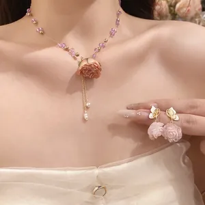 Detailed close-up of pink rose jewelry set including beaded necklace and butterfly earrings