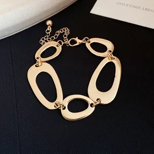 Close-up of golden chunky bracelet with irregular oval hollow links and adjustable chain.