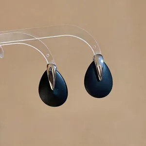 Minimalist matte black teardrop dangle earrings with polished silver accent.