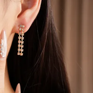 Close-up of elegant double-row rhinestone tassel drop earrings being worn on an ear