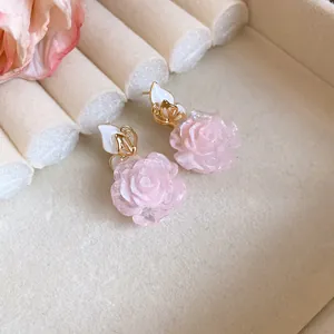 Elegant pink rose drop earrings with golden butterfly accents and soft velvet background