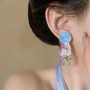 Detailed close-up of a summer-style seed bead earring with pink floral tassel on an ear.