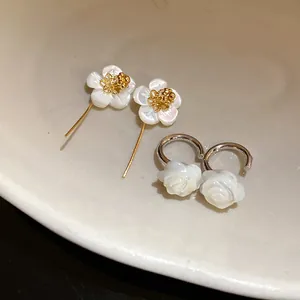 Detailed view of 18k gold plated shell flower and rose earrings in a vintage style.