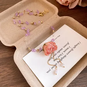Detailed macro view of the preserved pink rose pendant on a purple beaded necklace