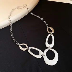 Close-up of silver irregular hollow oval pendants on a stylish statement necklace.