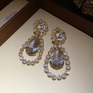 Close-up detail of luxurious water drop earrings with shimmering crystal rhinestones.