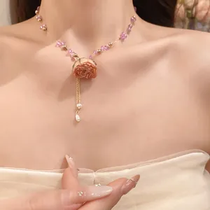Close-up detail of a sweet preserved rose pendant necklace with beads on a model neck