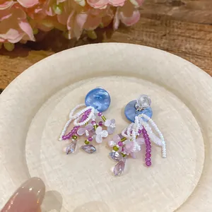 Detailed view of handmade beaded floral earrings with crystal pendants and blue accents