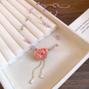 Detail shot of a handcrafted beaded necklace with a pink eternal flower pendant and pearls.