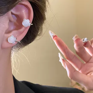 Close-up detail of white rose mother-of-pearl ear cuffs elegantly worn on model's ear