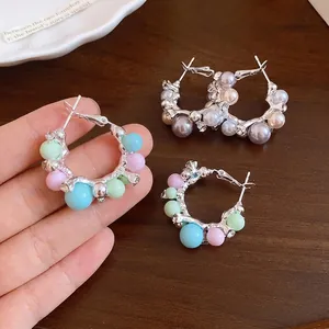 Élégantes créoles argentées avec perles pastel colorées sur un fond de bois foncé