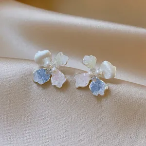 Detailed close-up view of flower stud earrings with pastel petals and pearl centers