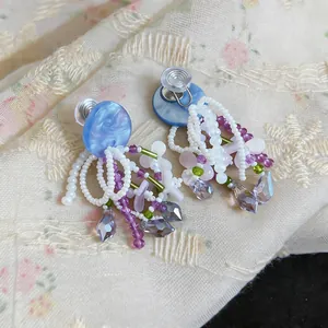 Detail view of colorful beaded earrings with flower charms and crystal drops.