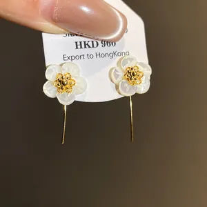 Close-up of mother-of-pearl flower earrings with 18k gold plated centers.