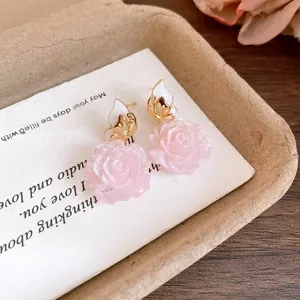 Macro detail of sweet pink rose petal earrings featuring elegant gold butterfly accents