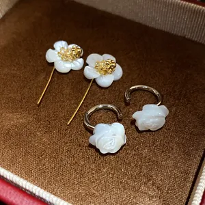 Detailed macro shot of vintage 18k gold plated white shell flower and rose hoop earrings set